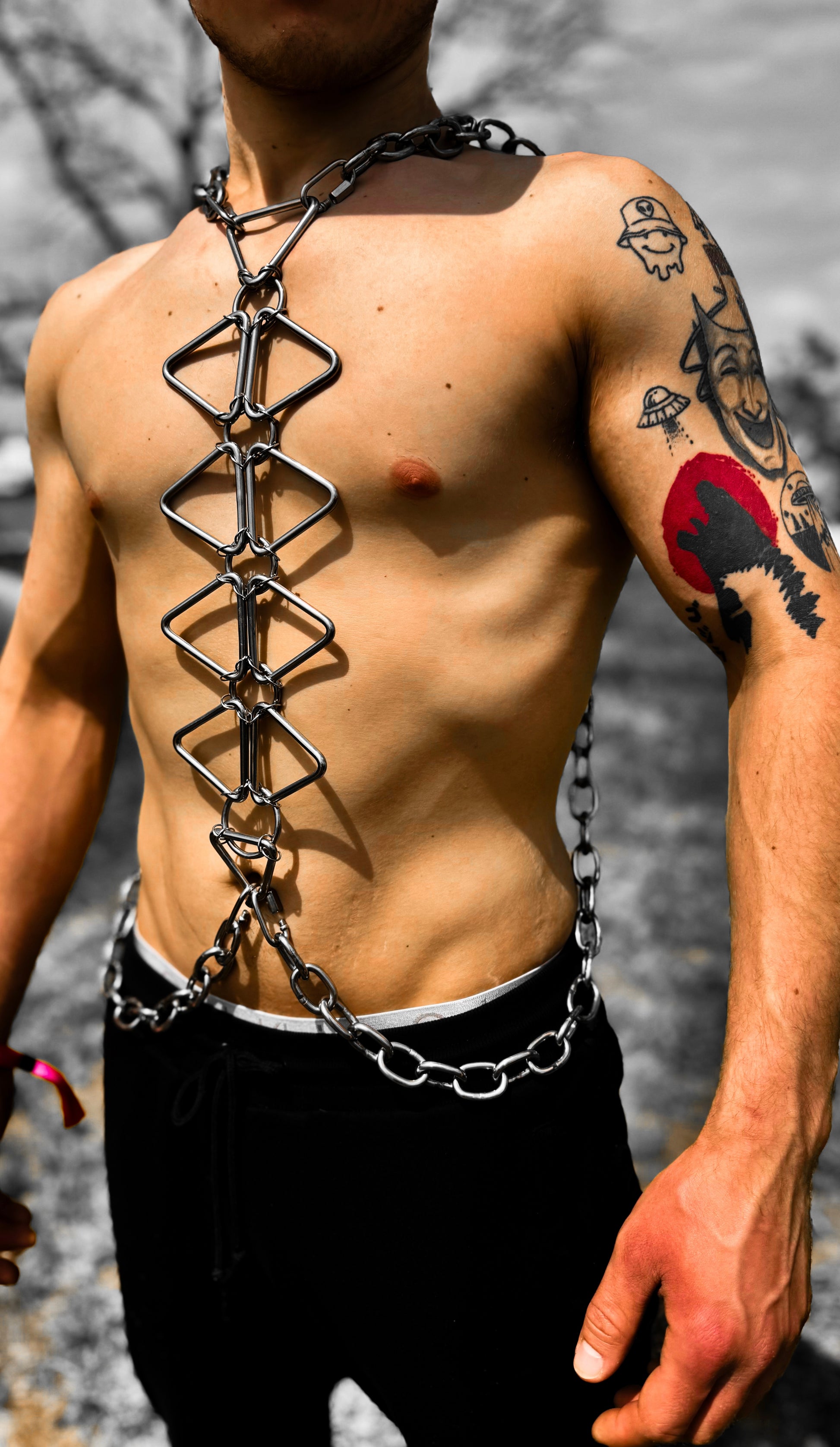 Stainless steel body chain made up of triangle, rings, and a thick chain on a man’s body